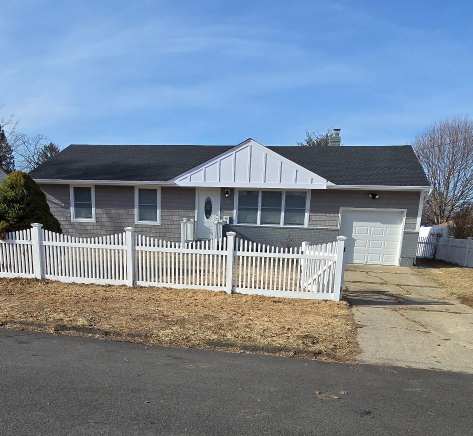 single story home featuring a fenced front yard, a garage, driveway, and a chimney