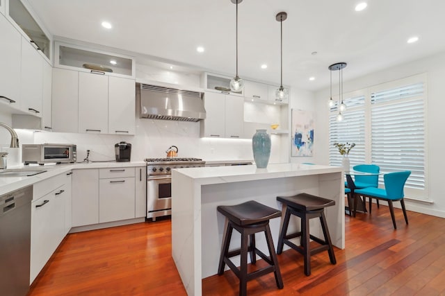 kitchen with a kitchen island, extractor fan, appliances with stainless steel finishes, and hardwood / wood-style flooring