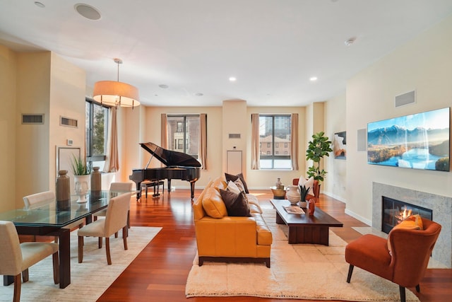 living room with visible vents, a fireplace with flush hearth, and wood finished floors