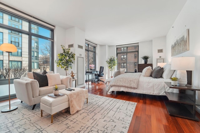 bedroom with expansive windows, multiple windows, and wood finished floors