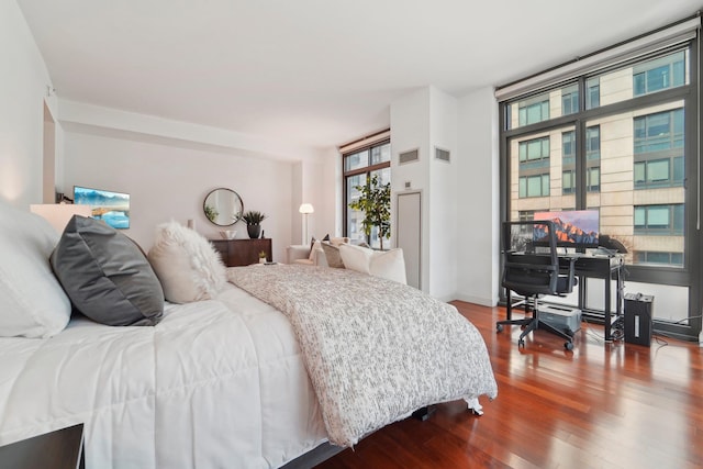 bedroom with wood finished floors, visible vents, and baseboards