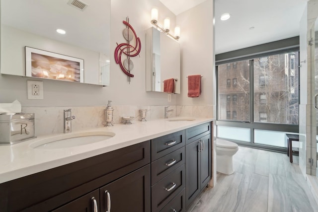 bathroom featuring a sink, visible vents, toilet, and double vanity