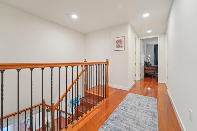 hall with wood finished floors, recessed lighting, an upstairs landing, and baseboards