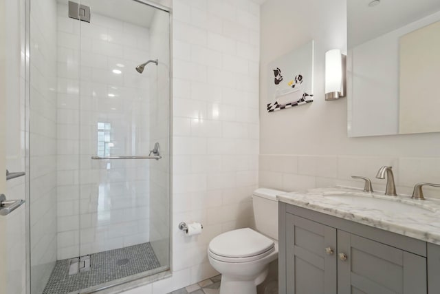 bathroom featuring vanity, tile walls, toilet, and a stall shower