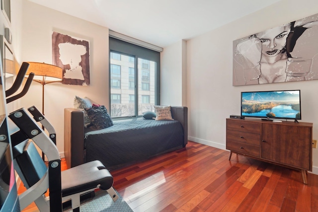 bedroom featuring baseboards, wood finished floors, and floor to ceiling windows