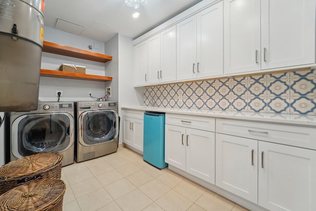 laundry area featuring washing machine and clothes dryer, light tile patterned floors, and cabinet space