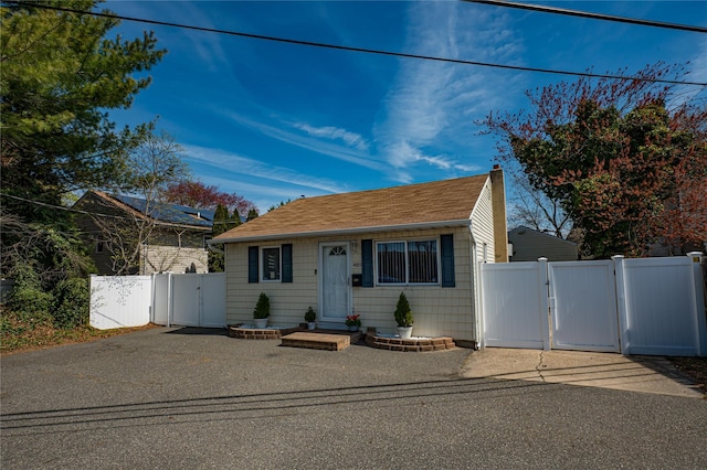bungalow-style home featuring a gate, fence, a shingled roof, and a chimney