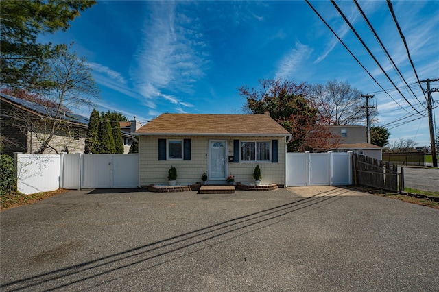 bungalow featuring a gate, fence, a shingled roof, and driveway