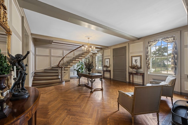 living area with stairs, a decorative wall, beamed ceiling, and a chandelier