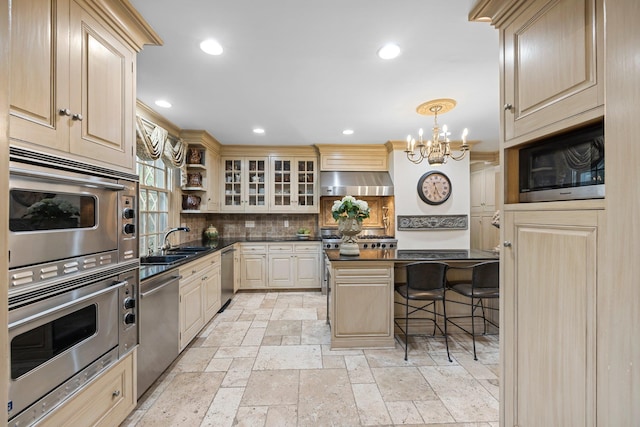 kitchen with under cabinet range hood, a sink, dark countertops, stainless steel appliances, and an inviting chandelier