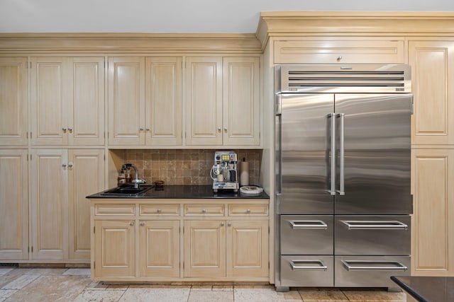 kitchen featuring dark countertops, cream cabinets, backsplash, and built in refrigerator