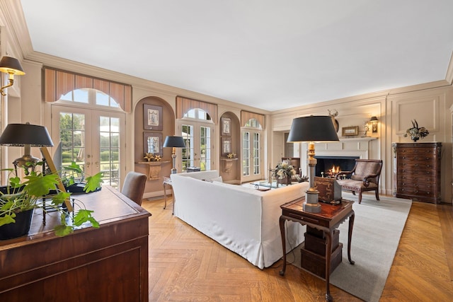 living room featuring french doors, a lit fireplace, ornamental molding, and a decorative wall