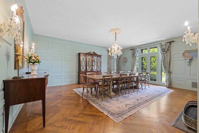 dining room with an inviting chandelier, a decorative wall, and french doors