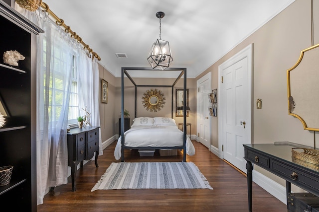 bedroom with visible vents, baseboards, a notable chandelier, and wood finished floors