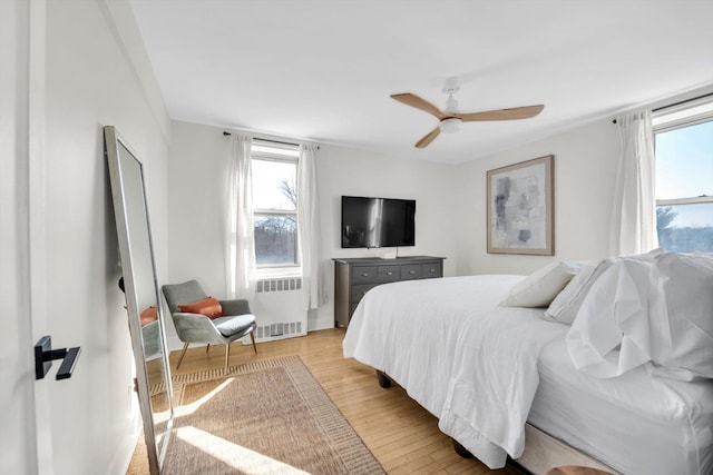 bedroom featuring ceiling fan, radiator heating unit, and light wood-style floors