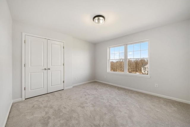 unfurnished bedroom with a closet, baseboards, and carpet flooring