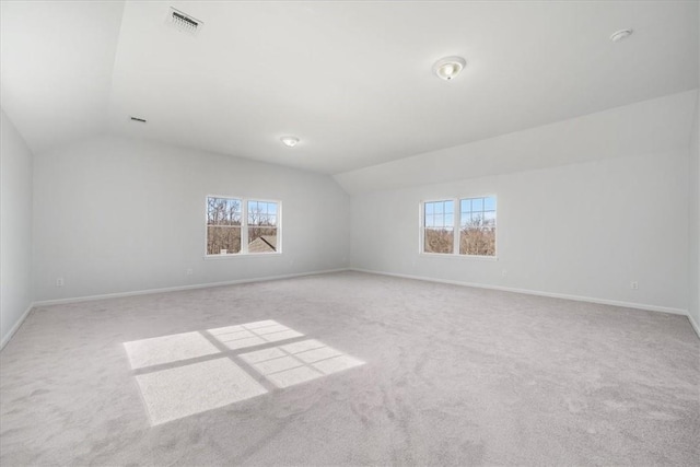 empty room with vaulted ceiling, carpet flooring, a healthy amount of sunlight, and baseboards