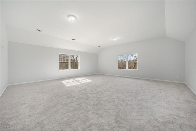 spare room with vaulted ceiling, a healthy amount of sunlight, visible vents, and light carpet