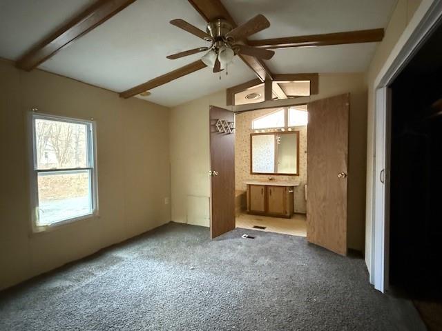 unfurnished bedroom with vaulted ceiling with beams and carpet