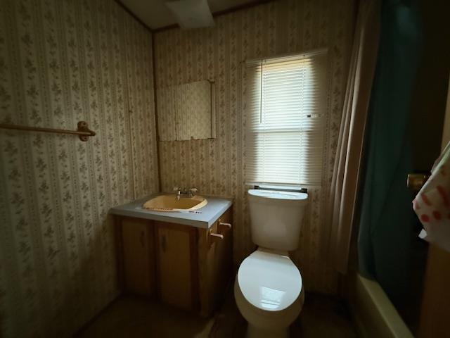 full bathroom with vanity, toilet, and wallpapered walls