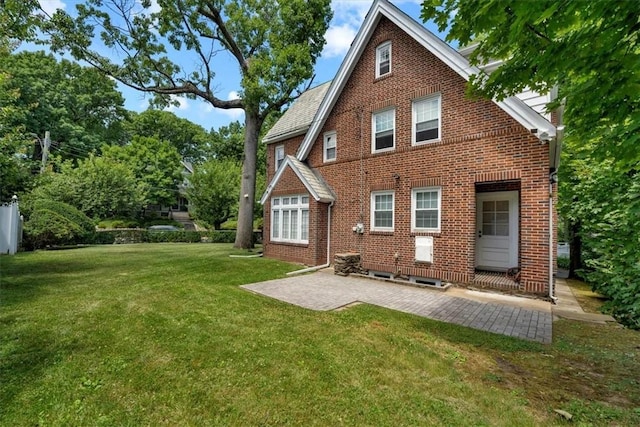 rear view of property featuring a yard, a patio area, and brick siding