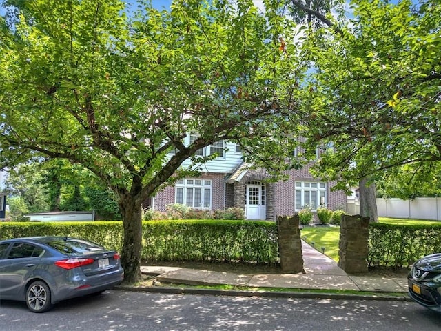 obstructed view of property featuring brick siding and fence