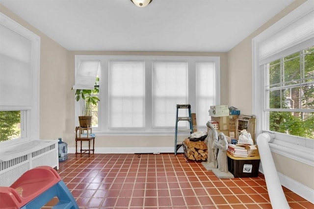 living area with a wealth of natural light, tile patterned flooring, radiator, and baseboards