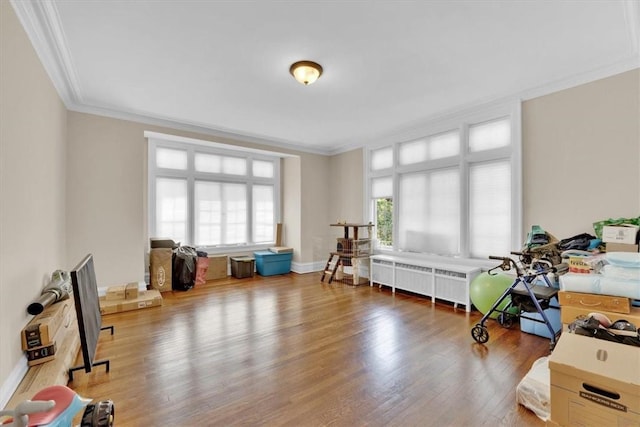 rec room featuring crown molding, radiator heating unit, wood finished floors, and baseboards