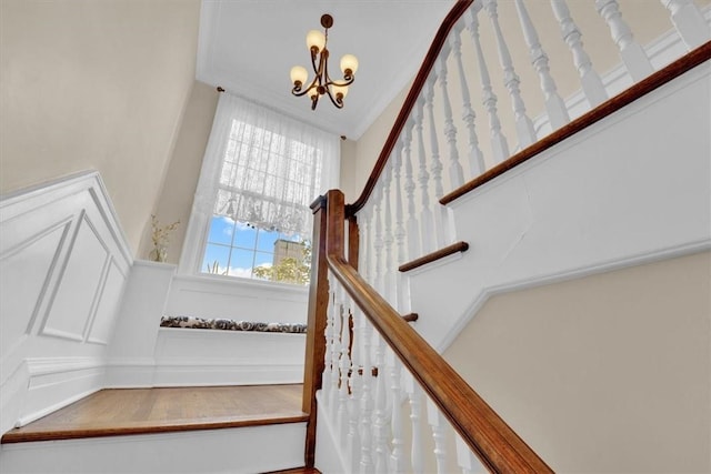 stairs with a notable chandelier and crown molding