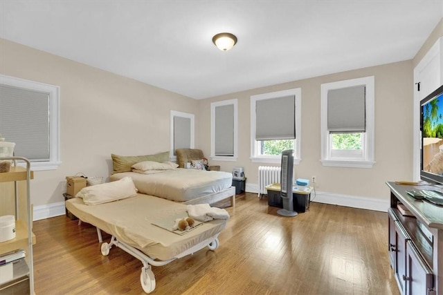 bedroom with radiator, baseboards, and wood finished floors