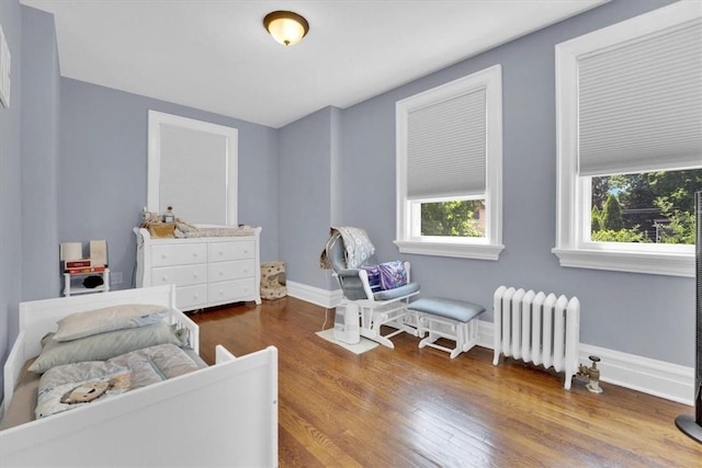 bedroom with radiator, baseboards, and wood finished floors