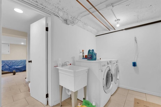 washroom with light tile patterned floors, laundry area, baseboards, and washing machine and clothes dryer