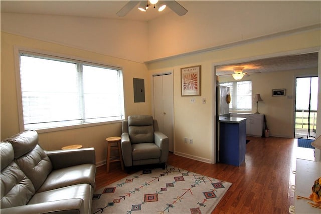 living area with a ceiling fan, electric panel, wood finished floors, baseboards, and vaulted ceiling