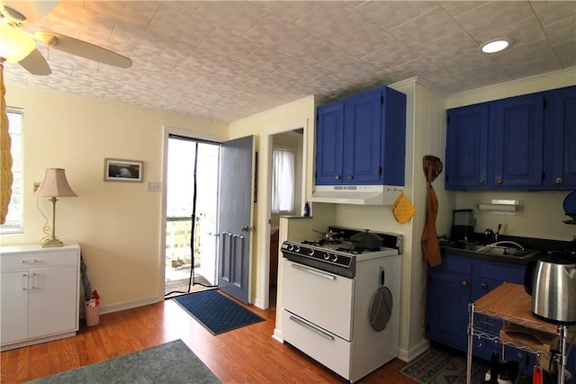 kitchen with under cabinet range hood, white range with gas cooktop, blue cabinetry, and a sink