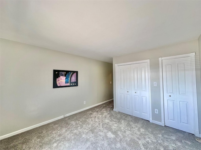 unfurnished bedroom featuring baseboards, multiple closets, and carpet floors