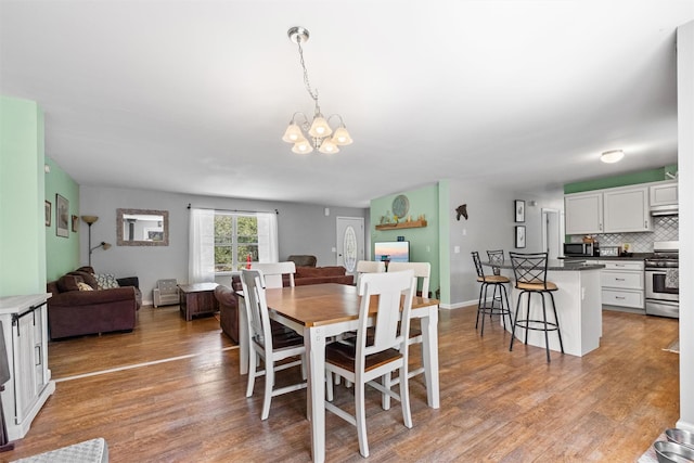 dining space with light wood finished floors and a notable chandelier
