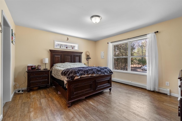 bedroom with baseboards, wood finished floors, and a baseboard radiator
