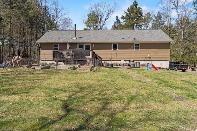back of property with a shingled roof, a yard, and a deck