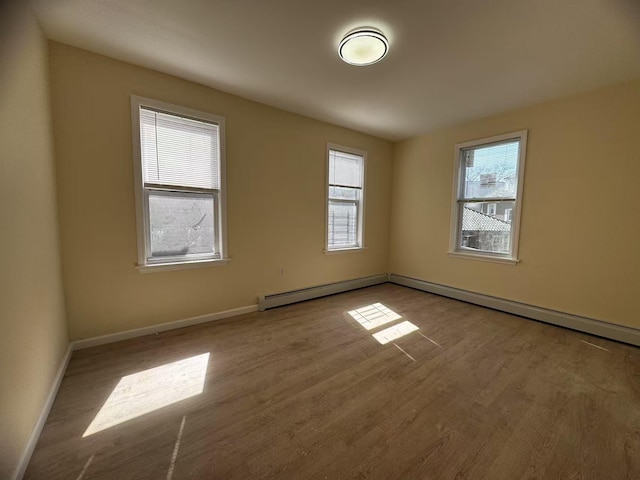 spare room featuring a wealth of natural light, baseboards, and wood finished floors