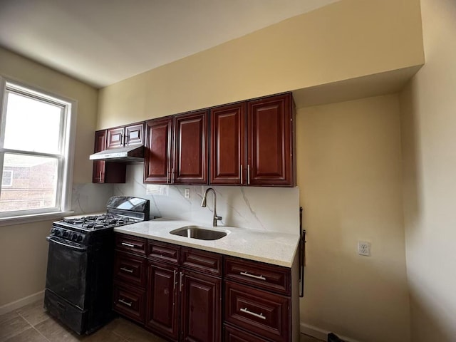 kitchen with black gas stove, a sink, dark brown cabinets, under cabinet range hood, and tasteful backsplash