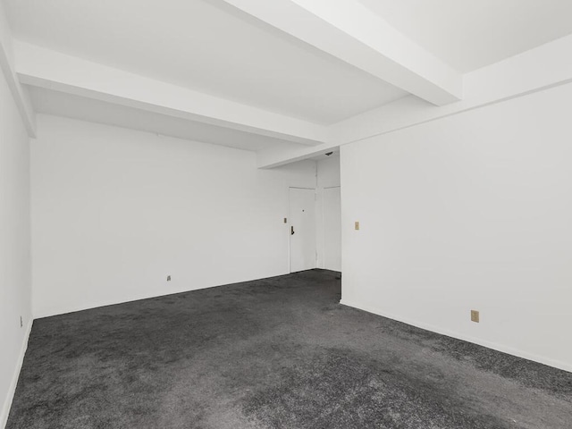 empty room with dark colored carpet and beam ceiling