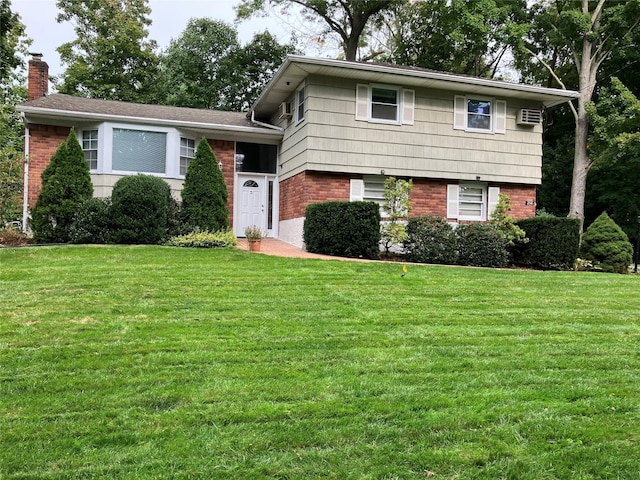 split level home with brick siding, a chimney, a front lawn, and a wall mounted AC