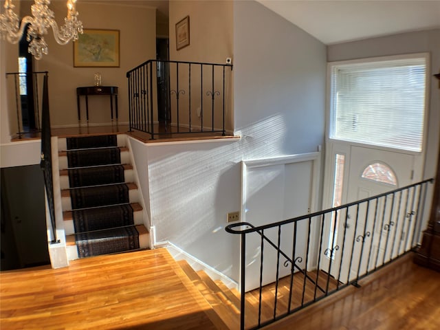 staircase with a chandelier and wood finished floors