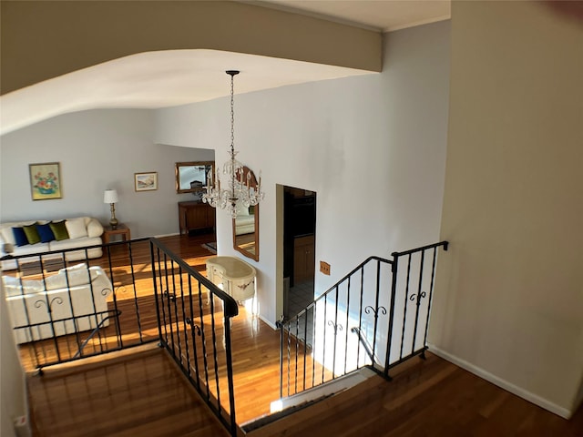 staircase with baseboards, a notable chandelier, lofted ceiling, and wood finished floors