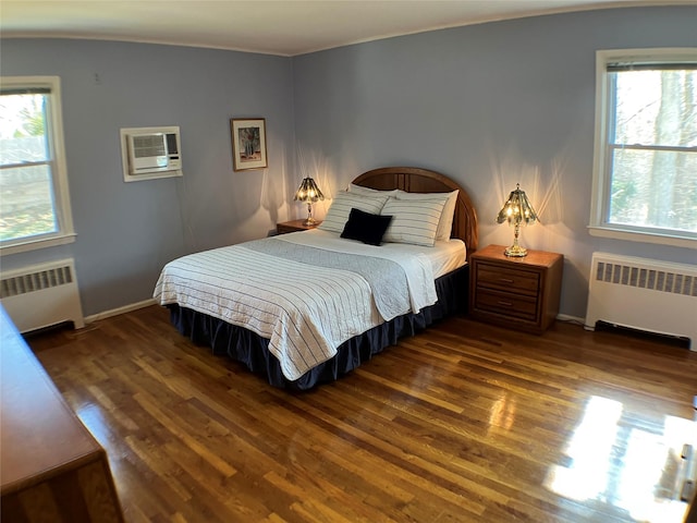 bedroom with dark wood-type flooring, radiator heating unit, baseboards, and a wall mounted AC