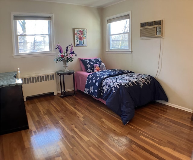 bedroom featuring an AC wall unit, radiator, dark wood-style floors, and baseboards