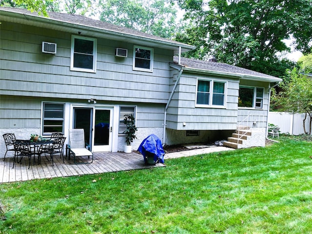 rear view of house with a lawn, a deck, and fence