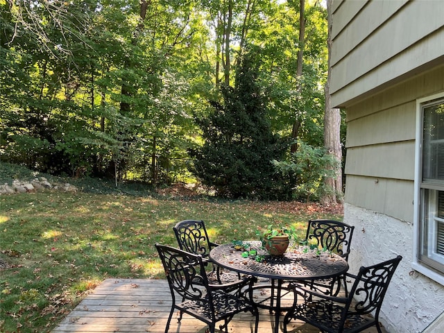 wooden terrace featuring outdoor dining space and a lawn