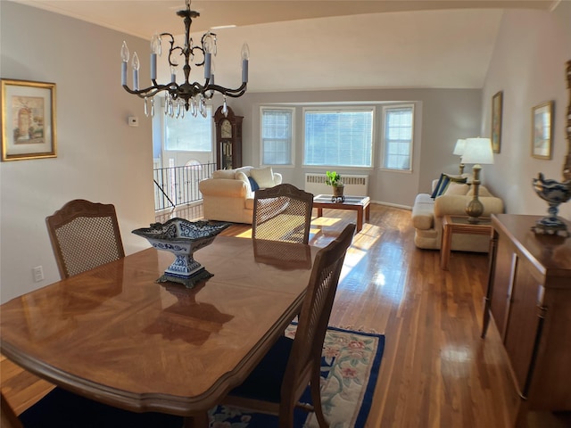 dining room with vaulted ceiling, a notable chandelier, radiator heating unit, and wood finished floors