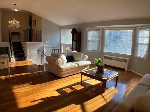 living area featuring a chandelier, vaulted ceiling, radiator heating unit, and wood finished floors